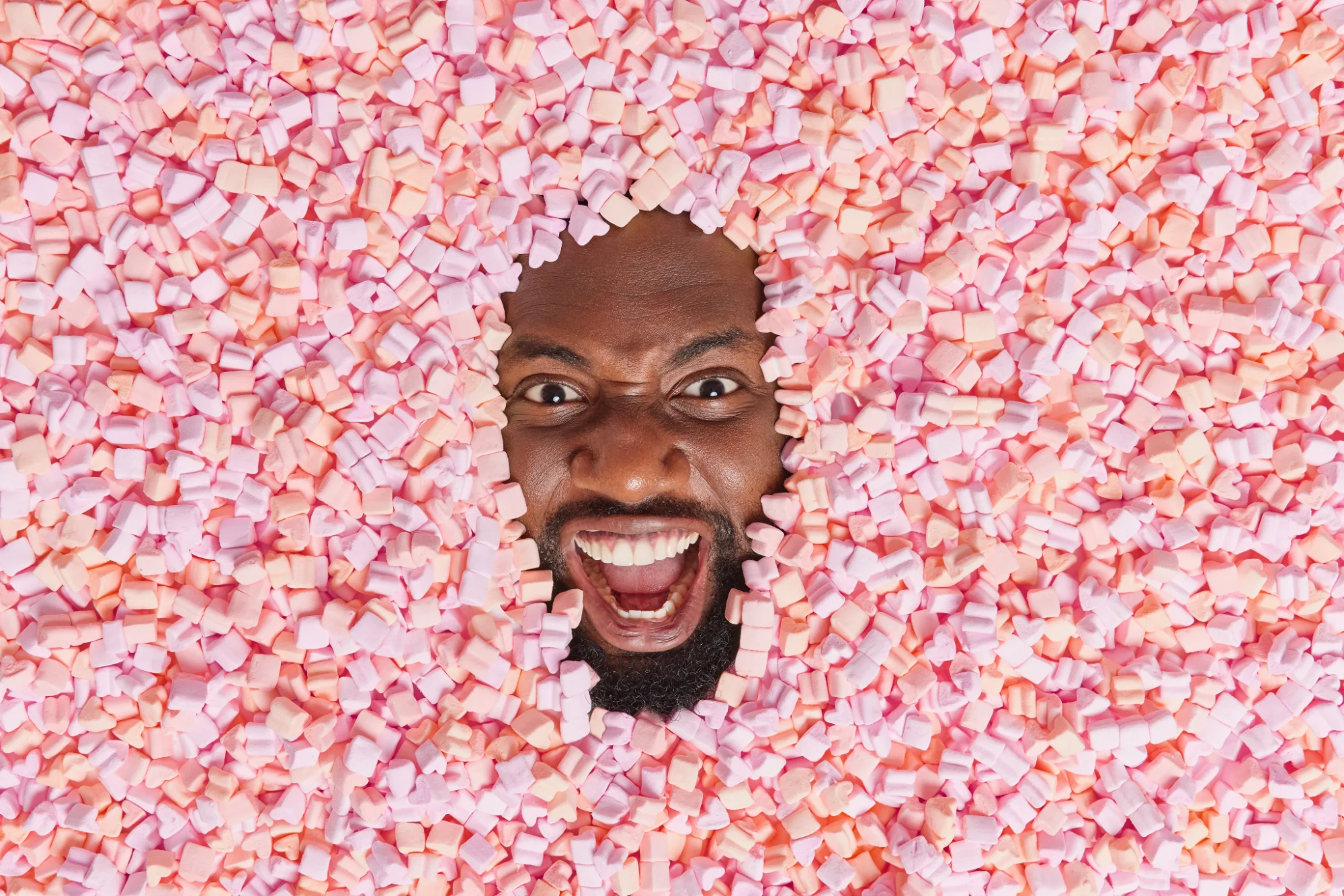 Man surrounded by pink and orange marshmallows 2026 03 17 02 40 22 utc